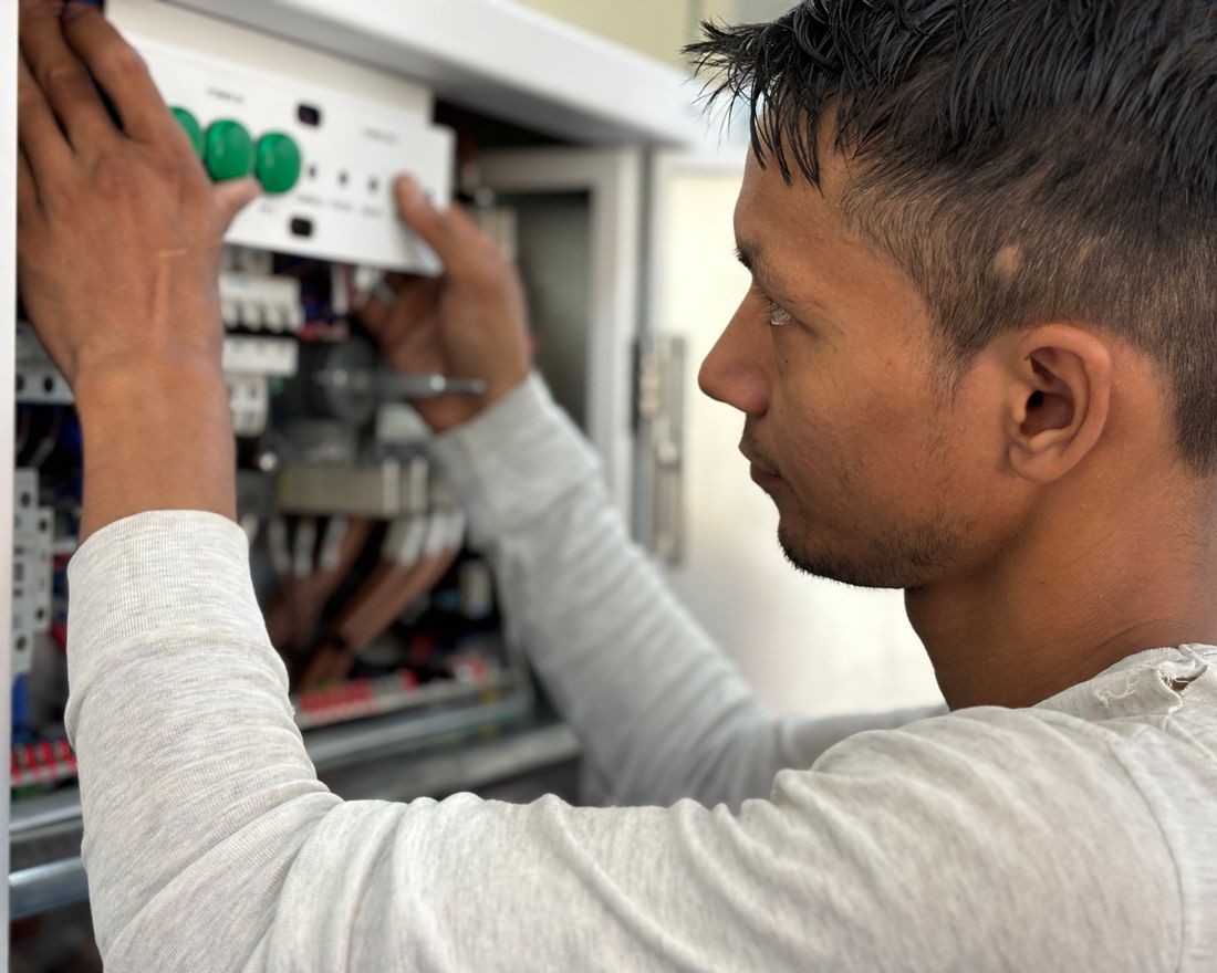 Eletricista trabalhando em um quadro elétrico com disjuntores